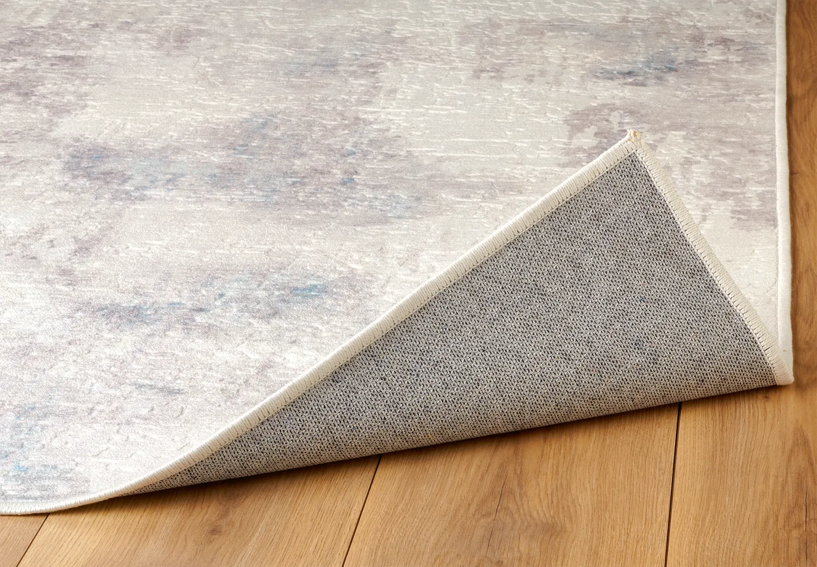 Angolo del tappeto Jorg PastBlue bouclé 3D con bordo rifinito e base antiscivolo.