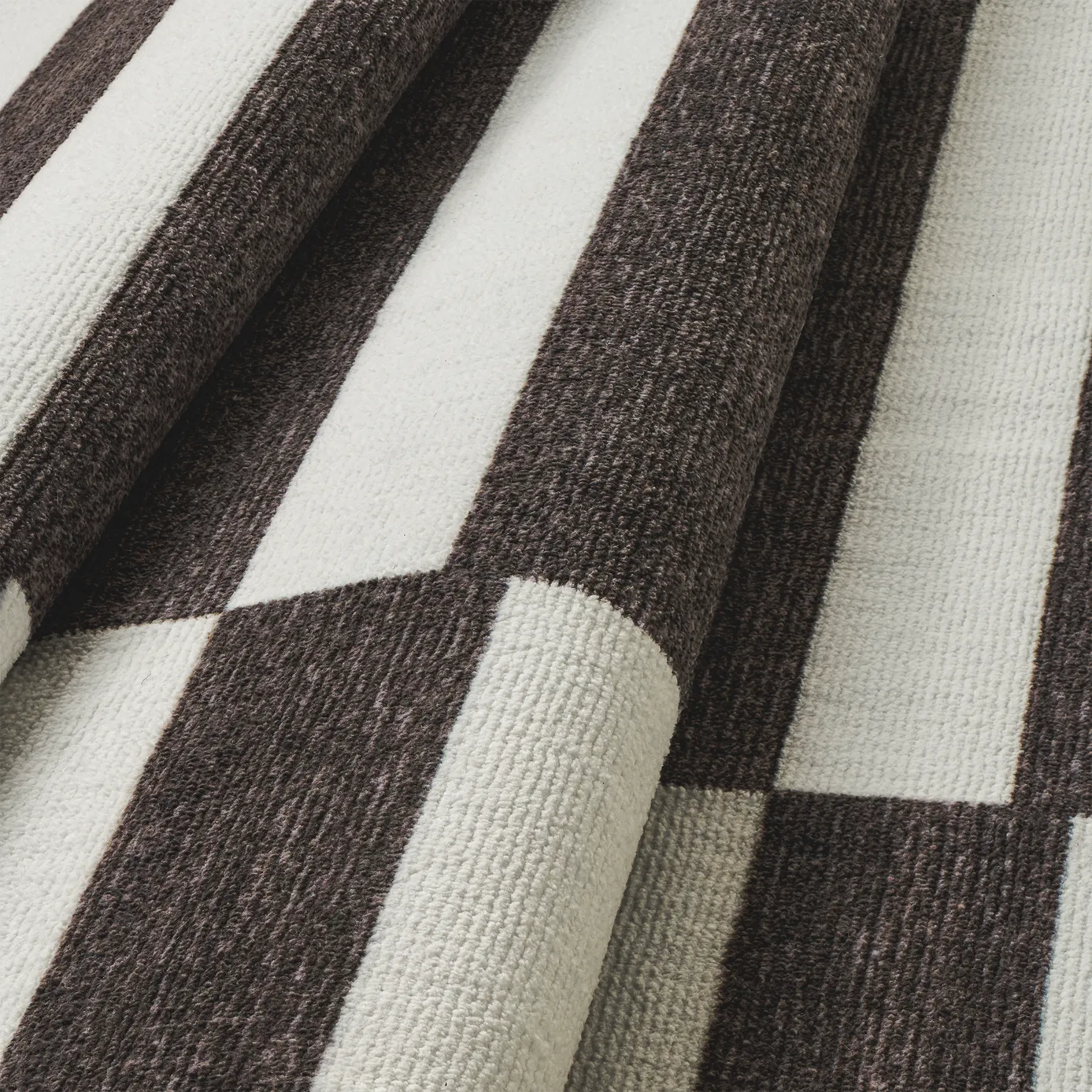 Dettaglio onda del tappeto Strider Black in pelo taftato effetto velluto, righe orizzontali allungate alternate nere e panna in colonne sfalsate