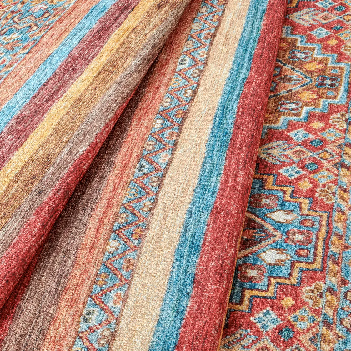 Dettaglio onda del tappeto Azmeo con motivi etnici e colori caldi.