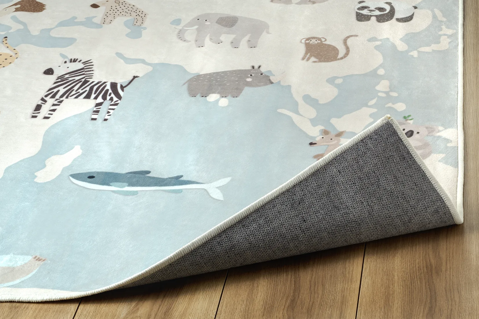 Angolo del tappeto Zoonia con bordo rifinito, parte di mappa del mondo e retro antiscivolo.