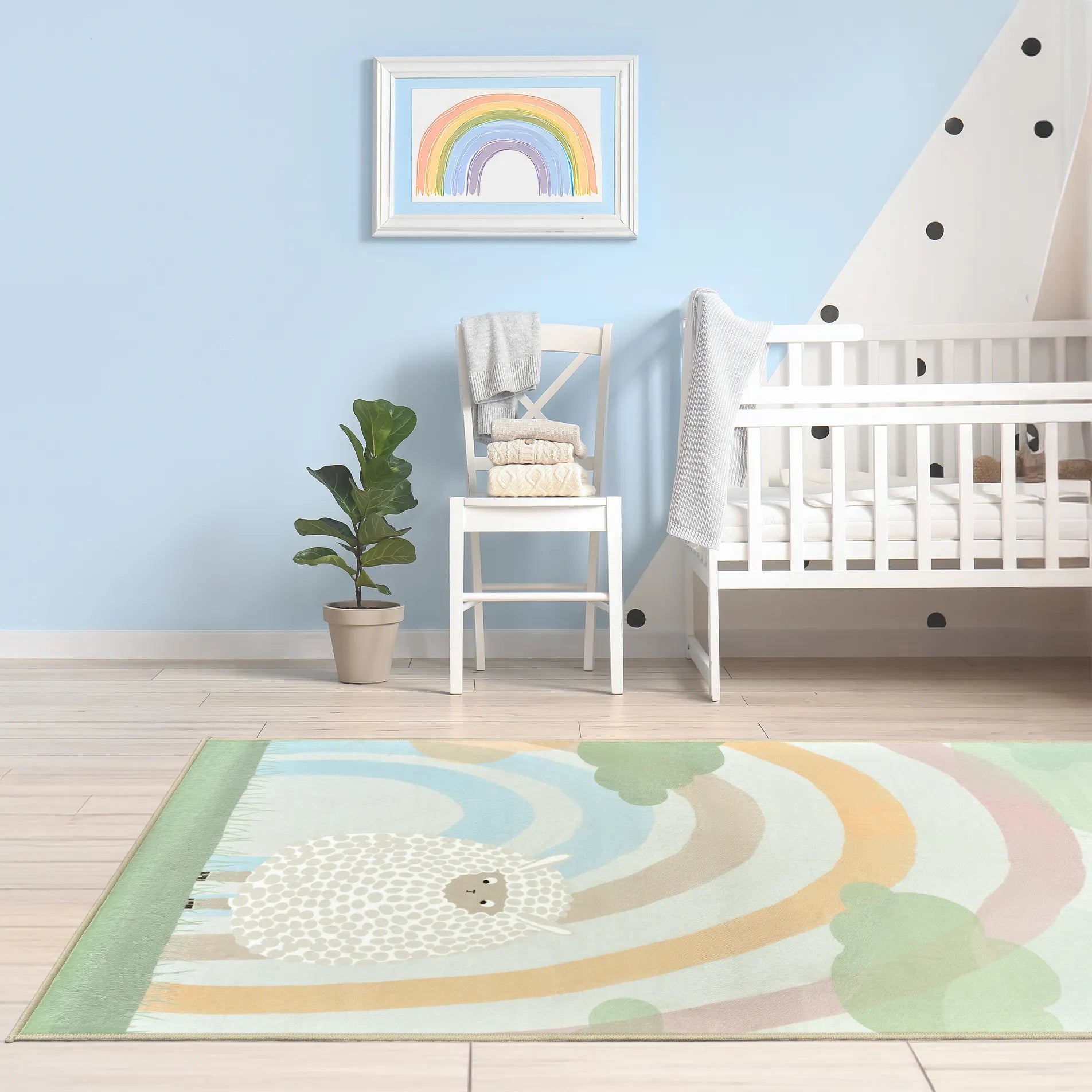 Tappeto Bella 80×150 cm in nursery con culla bianca, parete azzurra con pois e pianta in vaso; cornice con disegno arcobaleno sopra la sedia; lavabile in lavatrice a 40° e asciugabile in asciugatrice, antimacchia, antiscivolo e impermeabile.