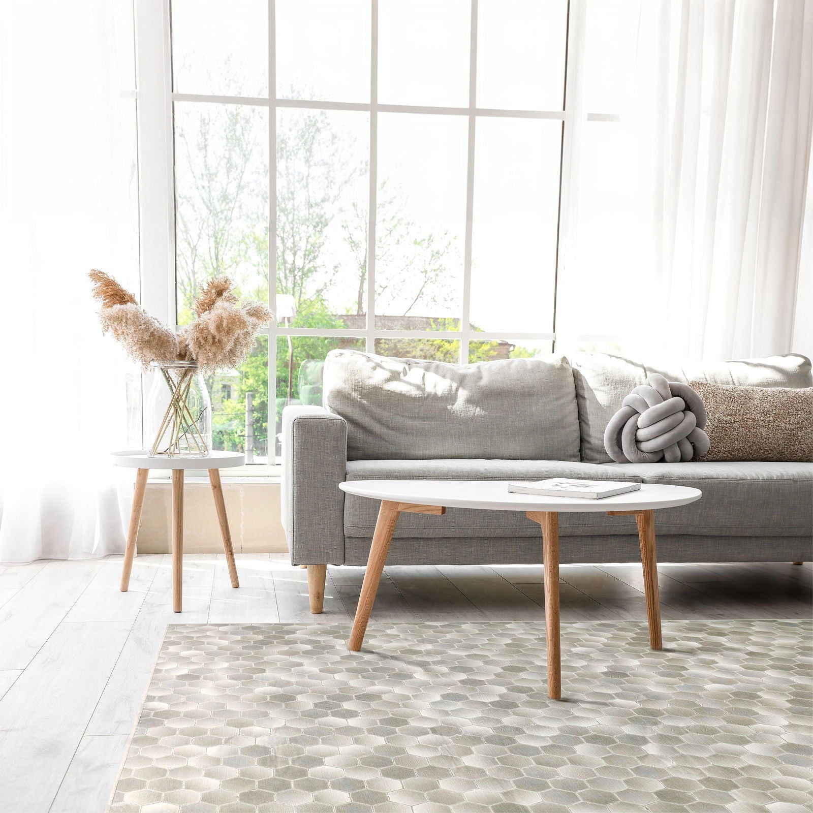 Tappeto Cotto 170×240 cm Lindorug posato davanti a un divano grigio chiaro con tavolino rotondo bianco e finestra panoramica
