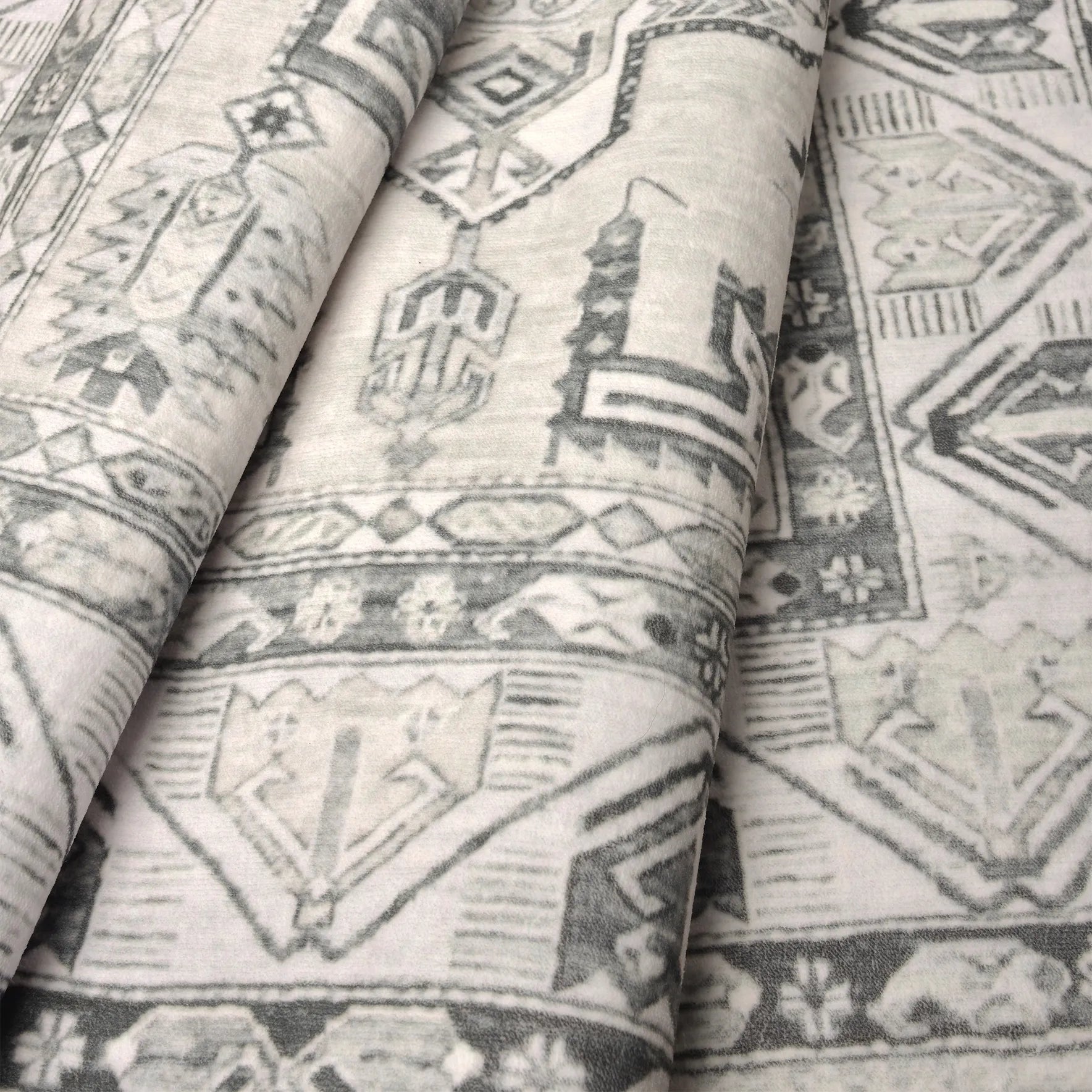 Dettaglio del tappeto Diamond che evidenzia la trama soffice e il motivo geometrico caucasico in avorio e grigio.