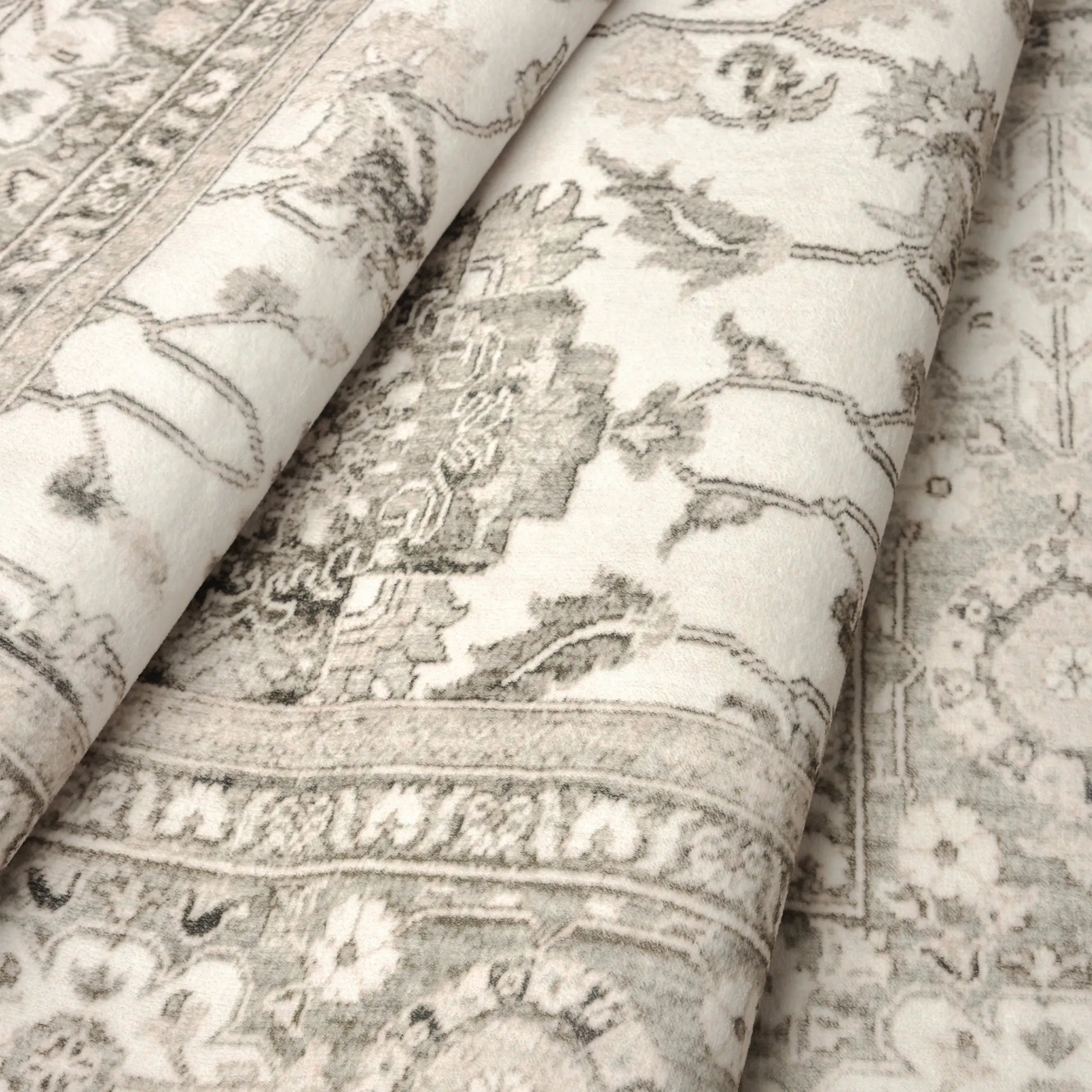 Dettaglio del tappeto Farah che mostra la trama a pelo corto e il motivo floreale persiano in tonalità avorio, beige e grigio.