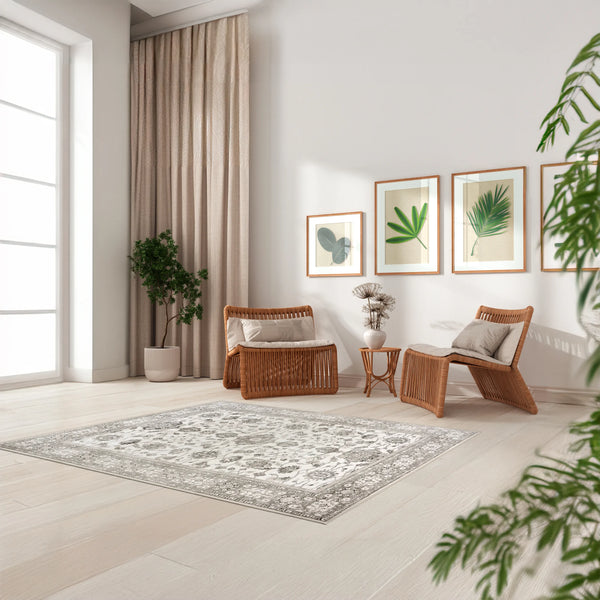 Tappeto Farah 160×230 cm beige e avorio con motivo floreale persiano, posizionato in un salotto luminoso con sedute in rattan, stampe botaniche e piante; lavabile e asciugabile.