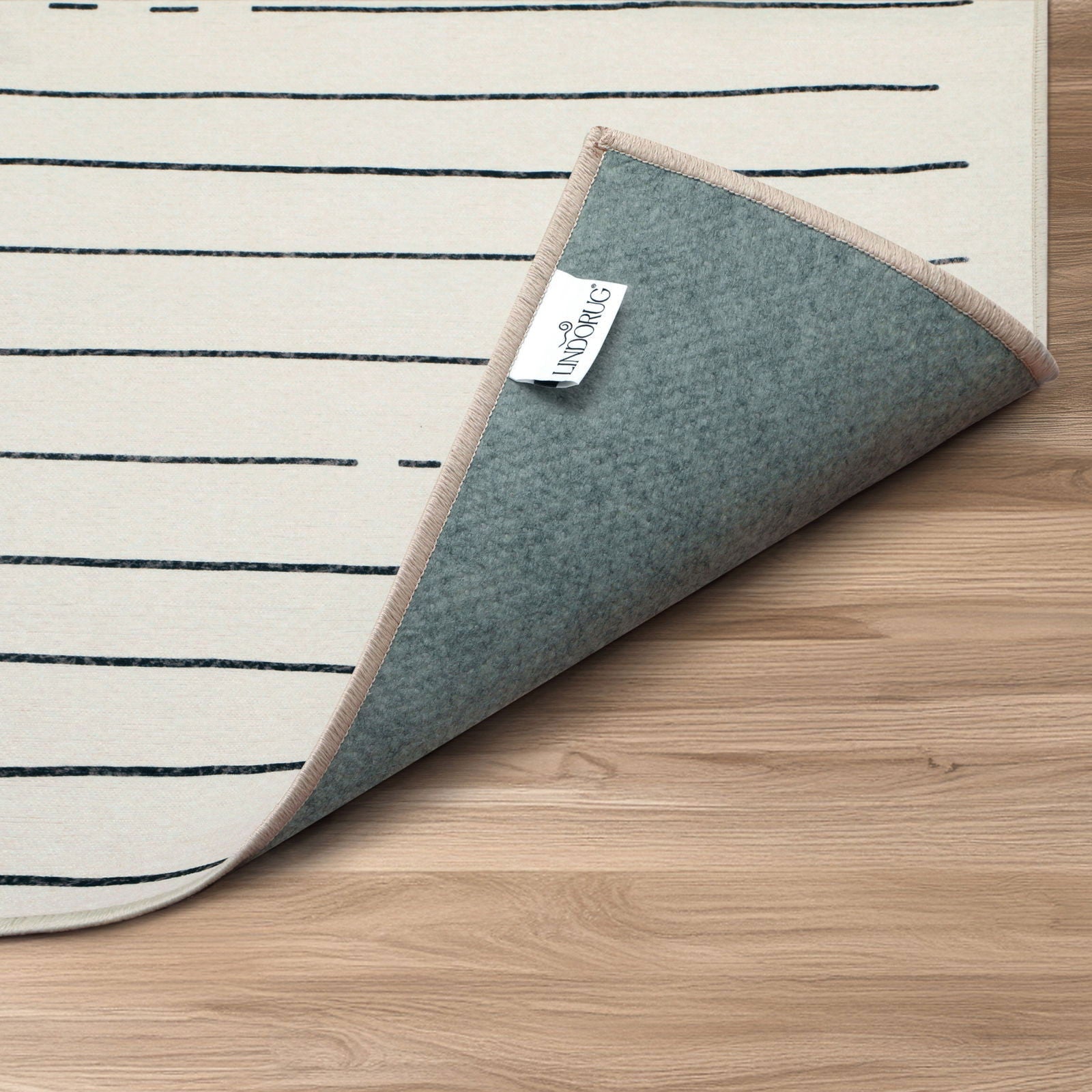 Dettaglio arrotolato tappeto Goza collezione Chenny mostra retro grigio ed etichetta con logo Lindorug