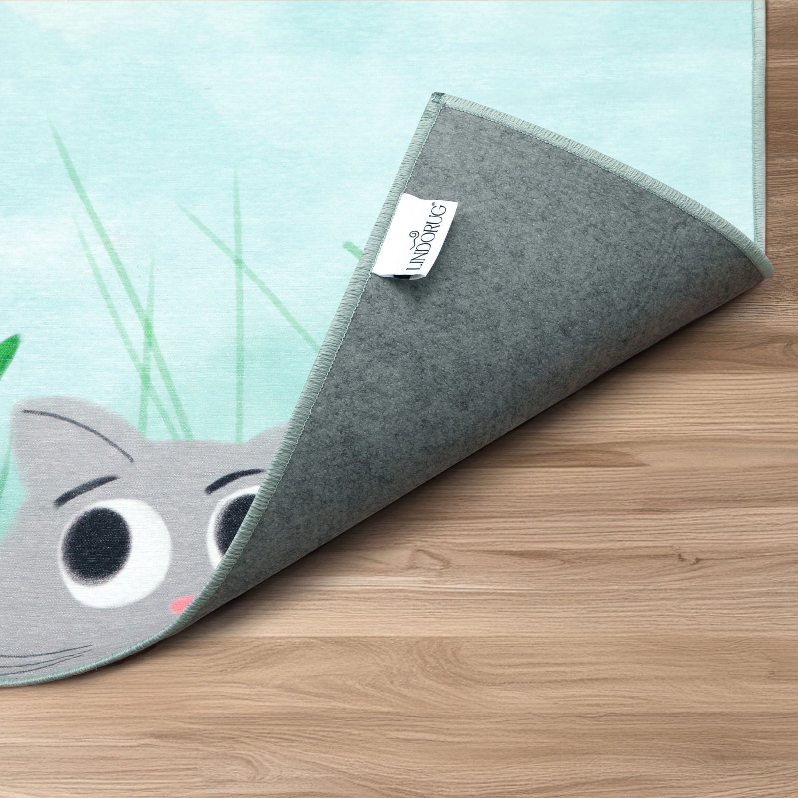 Dettaglio del bordo arrotolato del tappeto Kitty&Bee, collezione Chenny stile Kids con etichetta “Lindorug” visibile sul retro antiscivolo