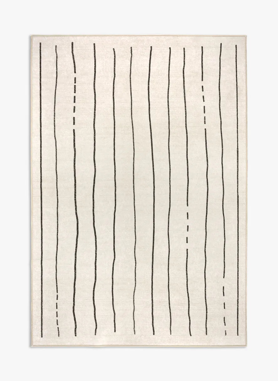 Tappeto Lead 130×190 cm crema con righe nere minimal; lavabile a 40° in lavatrice e asciugabile in asciugatrice, antiscivolo e impermeabile.