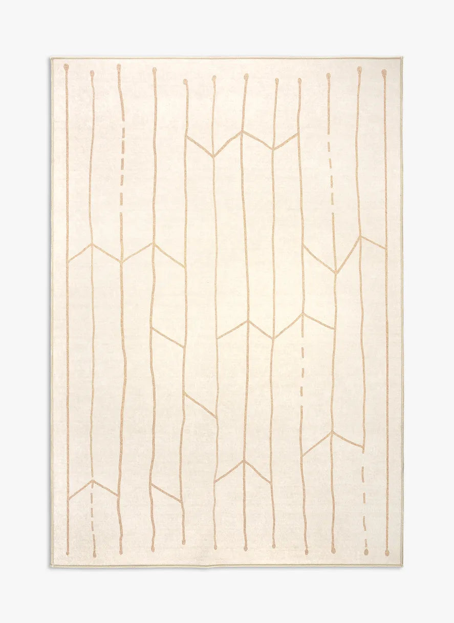 Tappeto Maira 130×190 cm crema e avorio con disegno tribale beige e tocco giallo oro; lavabile in lavatrice e asciugabile in asciugatrice, antiscivolo e impermeabile.