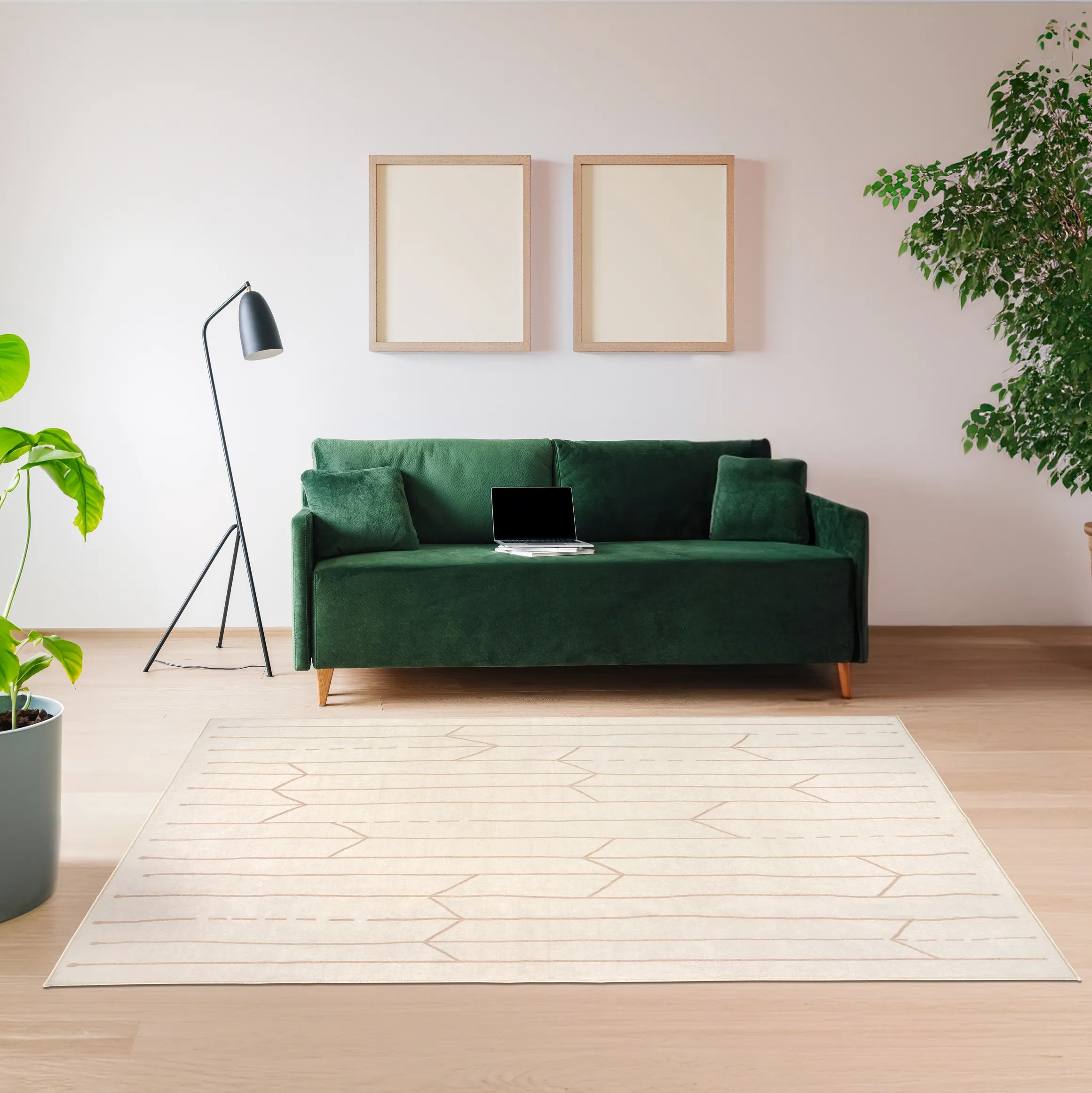Tappeto Maira 160×230 cm con motivo tribale beige su fondo crema, posizionato in un soggiorno moderno con divano verde, lampada nera e piante; lavabile in lavatrice e asciugabile in asciugatrice.