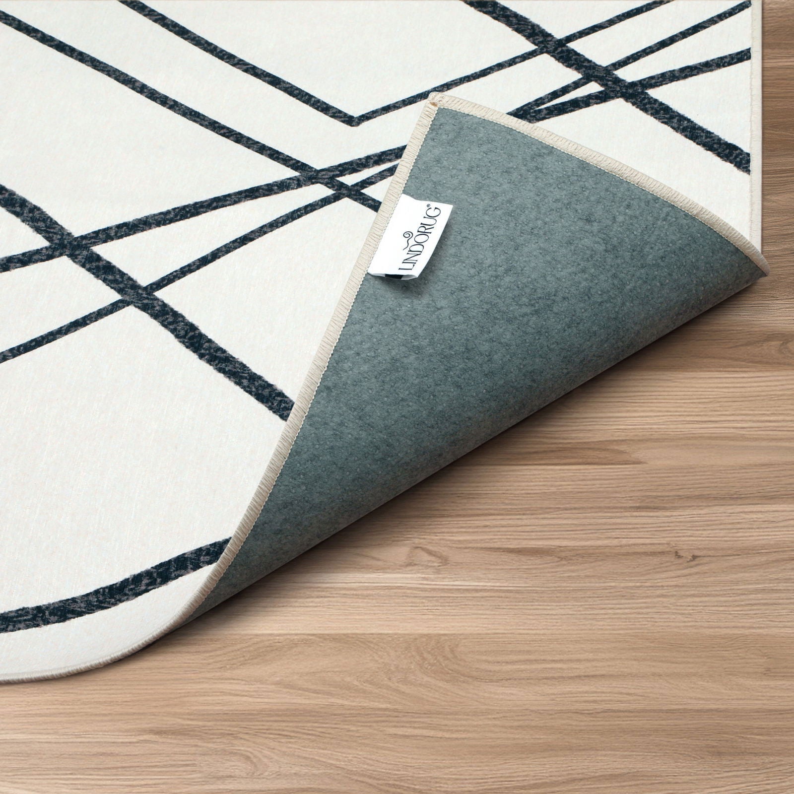 Dettaglio arrotolato tappeto Malik collezione Chenny mostra retro antiscivolo e logo Lindorug