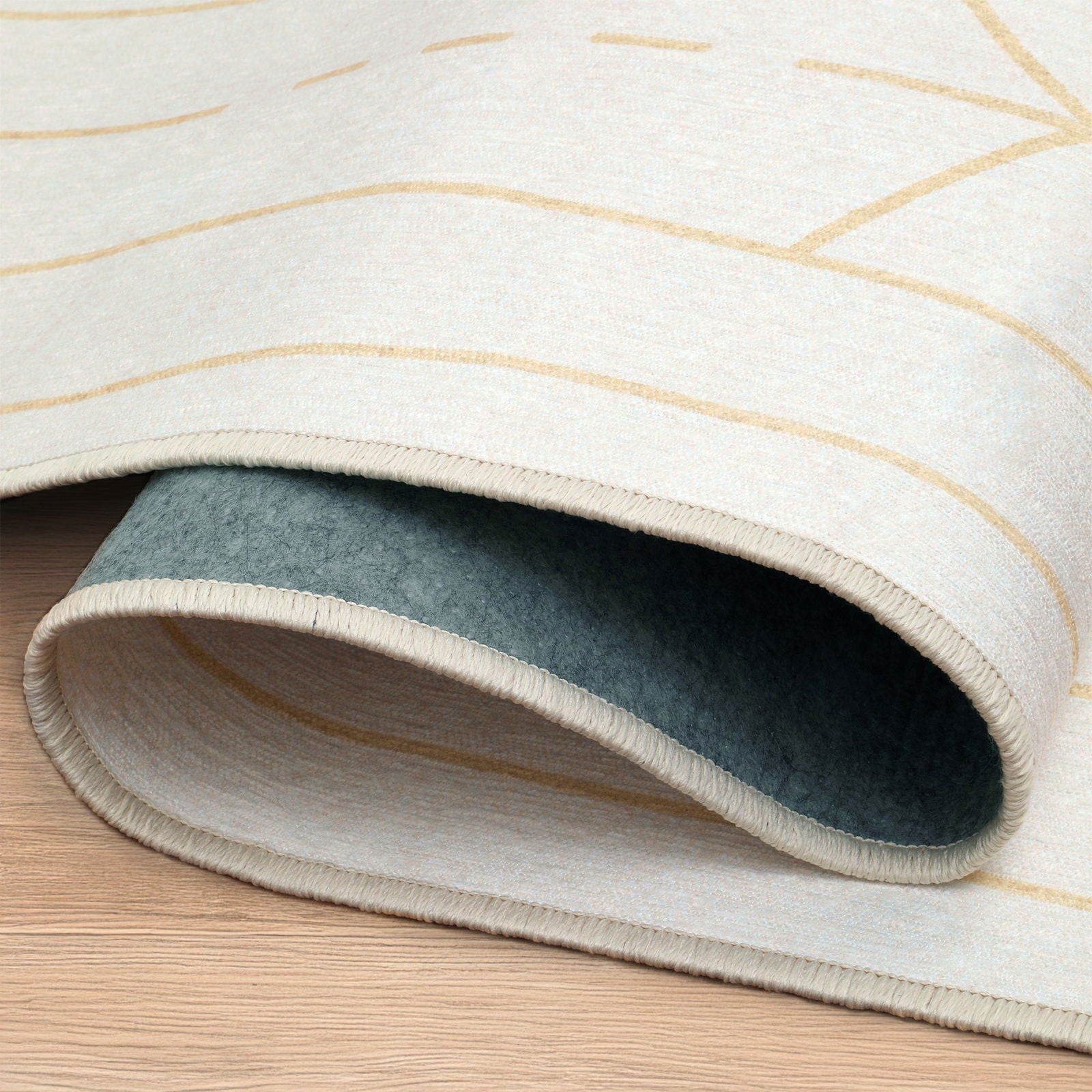 Primo piano bordo arrotolato del tappeto lavabile Mayra avorio e oro