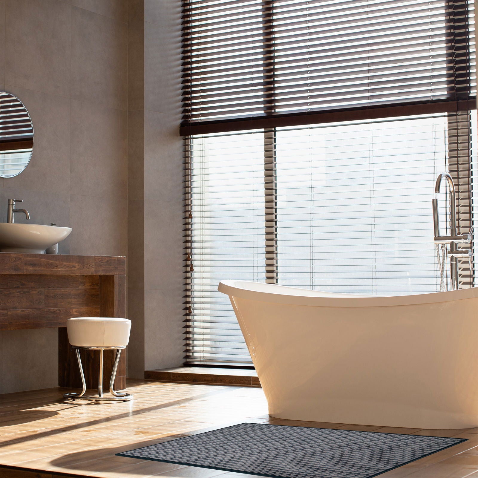 Tappeto Wiker 90×160 cm Lindorug steso davanti a una vasca da bagno bianca e persiane in legno scuro